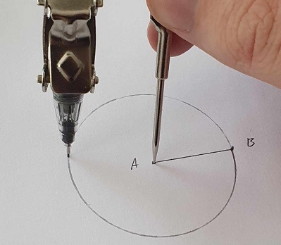 A compass being used to rotate a pen around a point to draw a circle