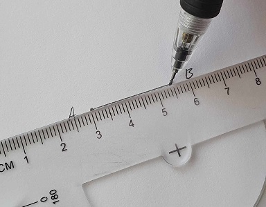 A ruler being used to draw a straight line